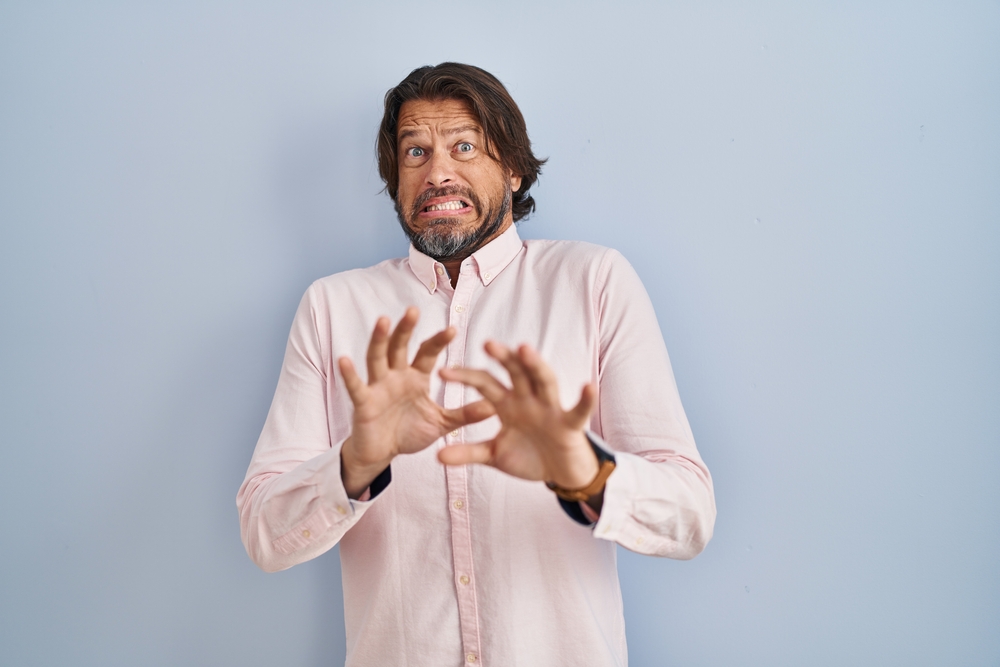 Autistic bearded man horrified by food near mouth 