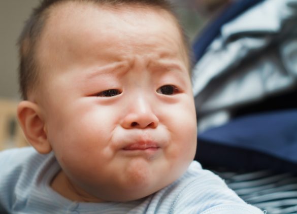 A close up photo of a baby who looks like they are about to cry.
