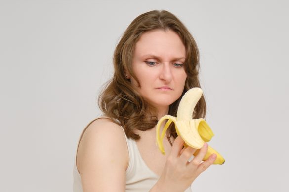 A person with short hair stares contemptuously at a half-peeled banana.
