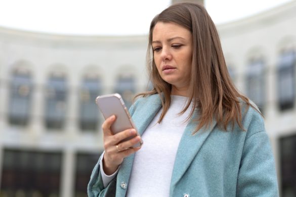 A woman looking at a phone with a disappointed expression