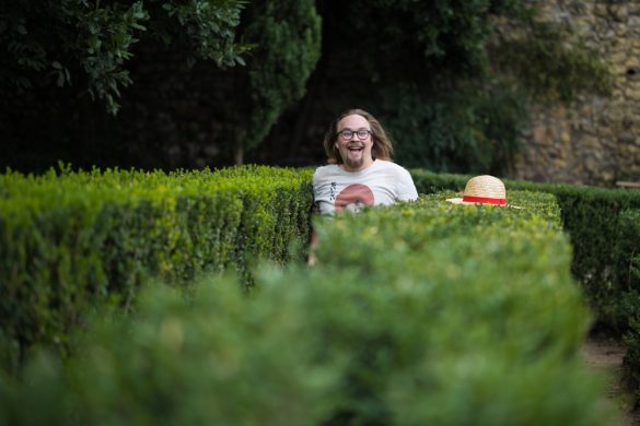 A man happily walking through a hedge maze
